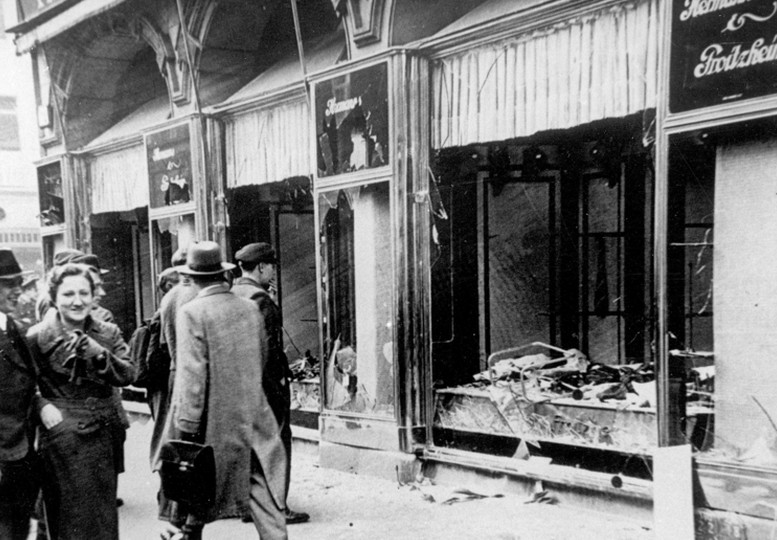 Maagdenburg, na de Kristallnacht van 9–10 november 1938. Een koppel loopt lachend voorbij ingeslagen winkelramen. Koblenz, Bundesarchiv